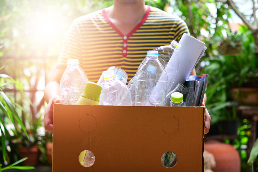 Personne portant une caisse comprenant des déchets recyclables